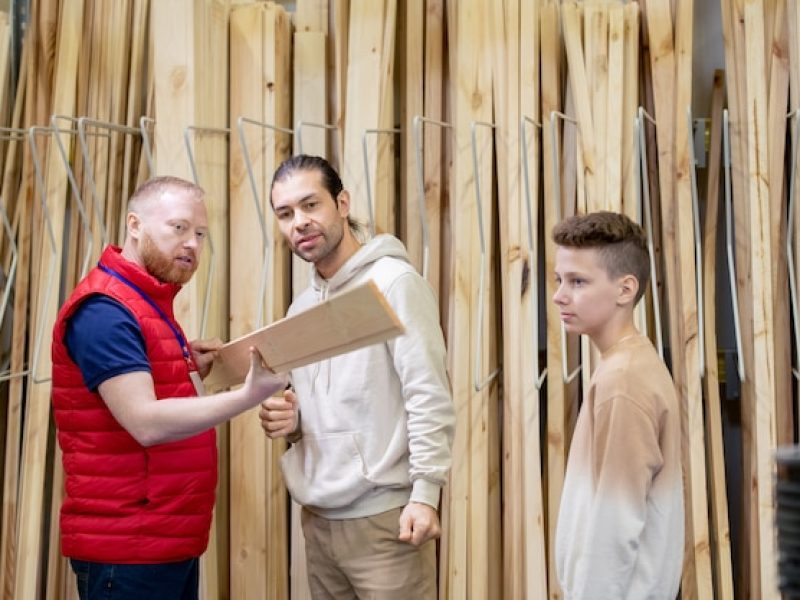 bearded-shop-assistant-showing-wooden-board-buyers-hardware-store_274679-21160