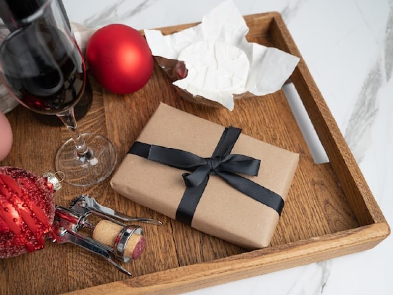 christmas-composition-wit-red-wine-cheese-wrapped-gift-wooden-tray_542154-104