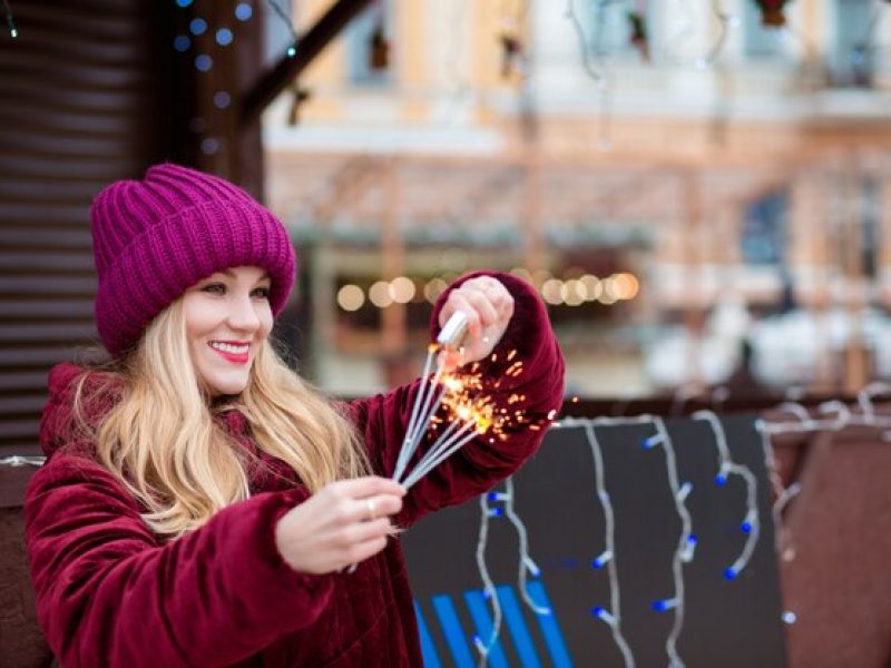 happy-blonde-girl-dressed-stylish-clothes-sets-fire-sparklers-christmas-fair-kiev_172420-12314