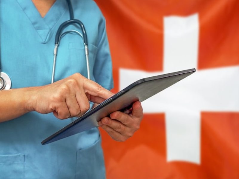 surgeon-doctor-using-digital-tablet-background-switzerland-flag_156719-812