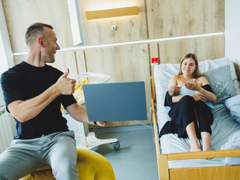 young-man-works-laptop-against-background-his-wife-who-is-breastfeeding-her-newborn-child-work-online-laptop_173815-46923