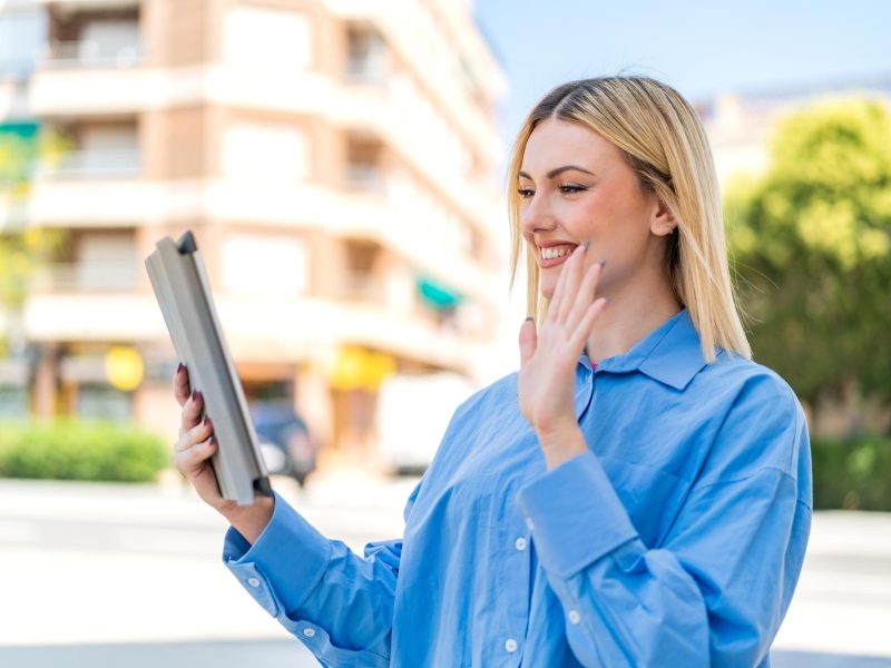 young-pretty-blonde-woman-outdoors-holding-tablet-saluting_1368-512943