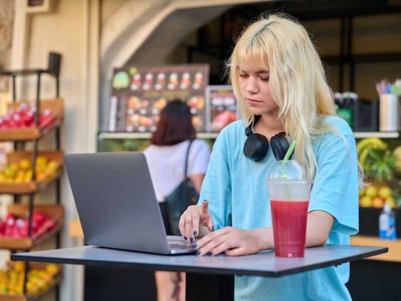 young-woman-outdoor-cafe-with-fruit-fresh-juice-using-laptop_116407-20363